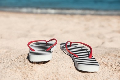 Striped flip flops on sandy beach near sea