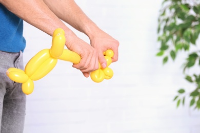 Man making balloon figure on blurred background, closeup. Space for text