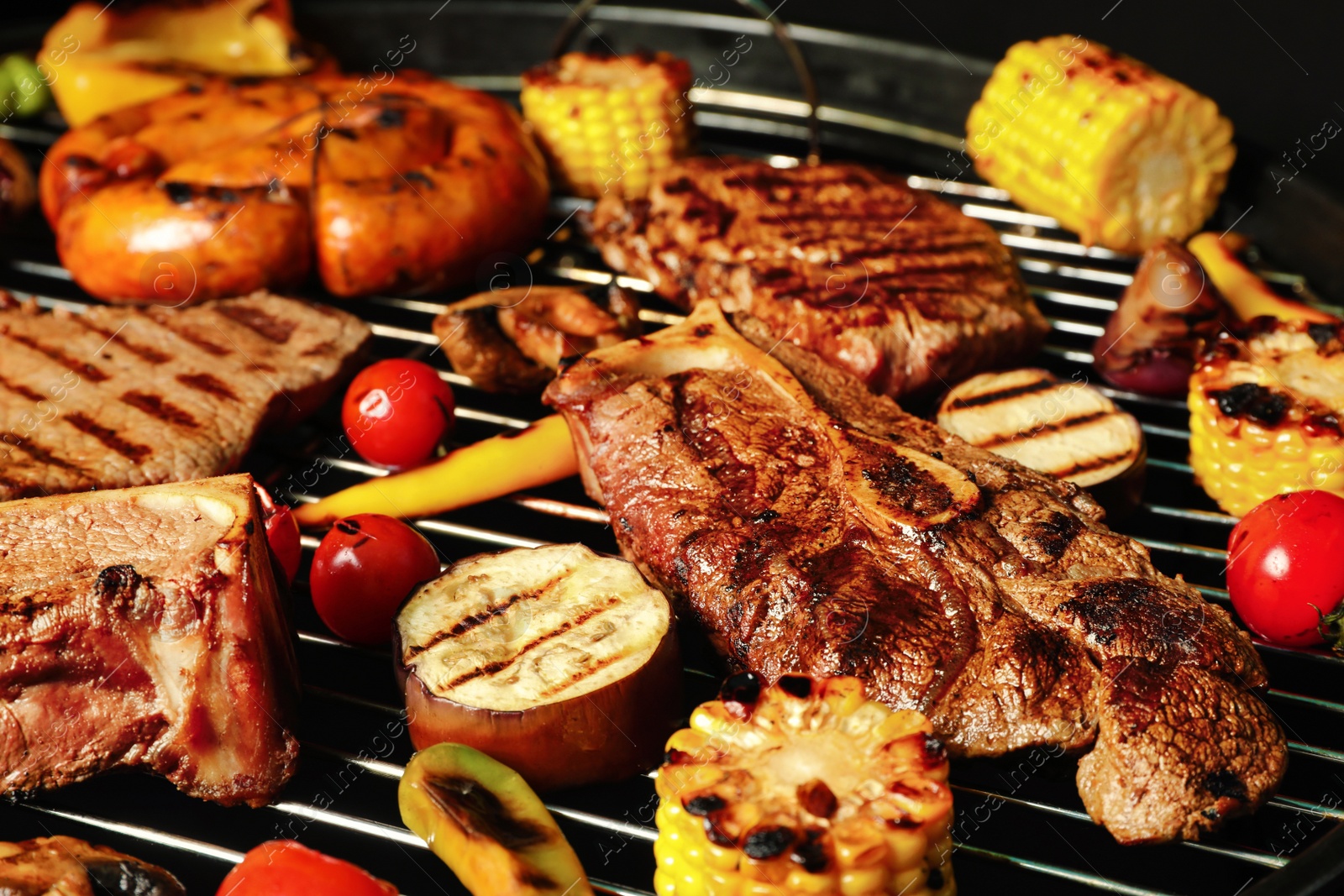 Photo of Fresh grilled meat steaks and vegetables on barbecue grate, closeup