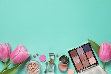 Flat lay composition with eyeshadow palette and beautiful flowers on turquoise background, space for text