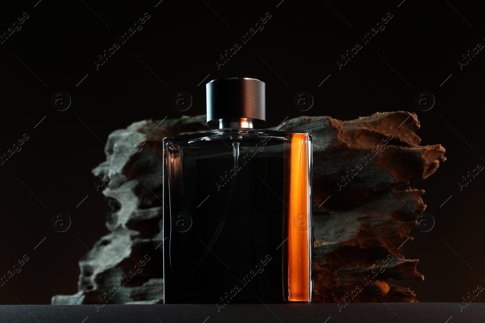 Photo of Luxury men`s perfume in bottle on grey table against dark background