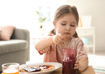 Photo of Little girl with jam and toasts in living room