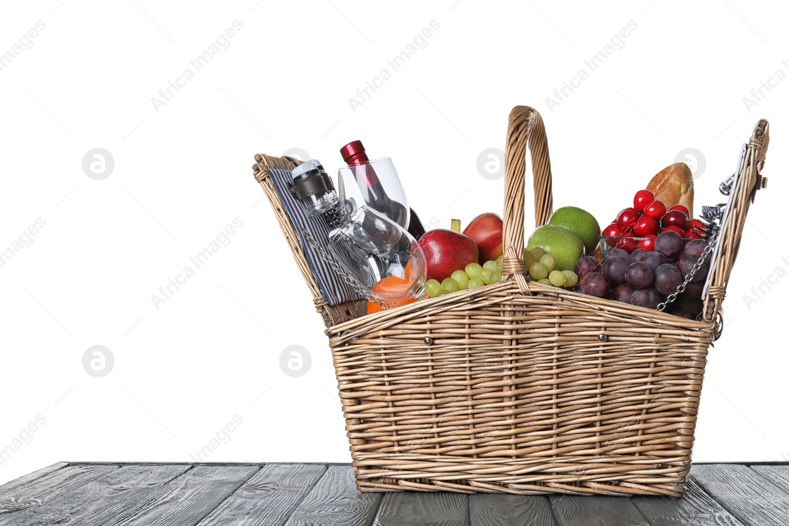 Photo of Wicker picnic basket with wine and different products on wooden table against white background, space for text