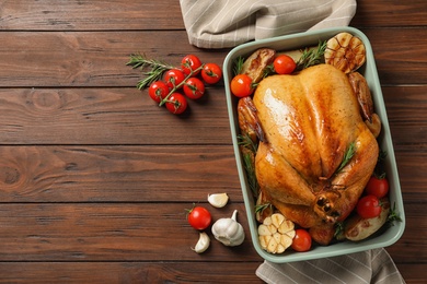 Photo of Cooked turkey with vegetables and rosemary in dish on wooden background, flat lay. Space for text