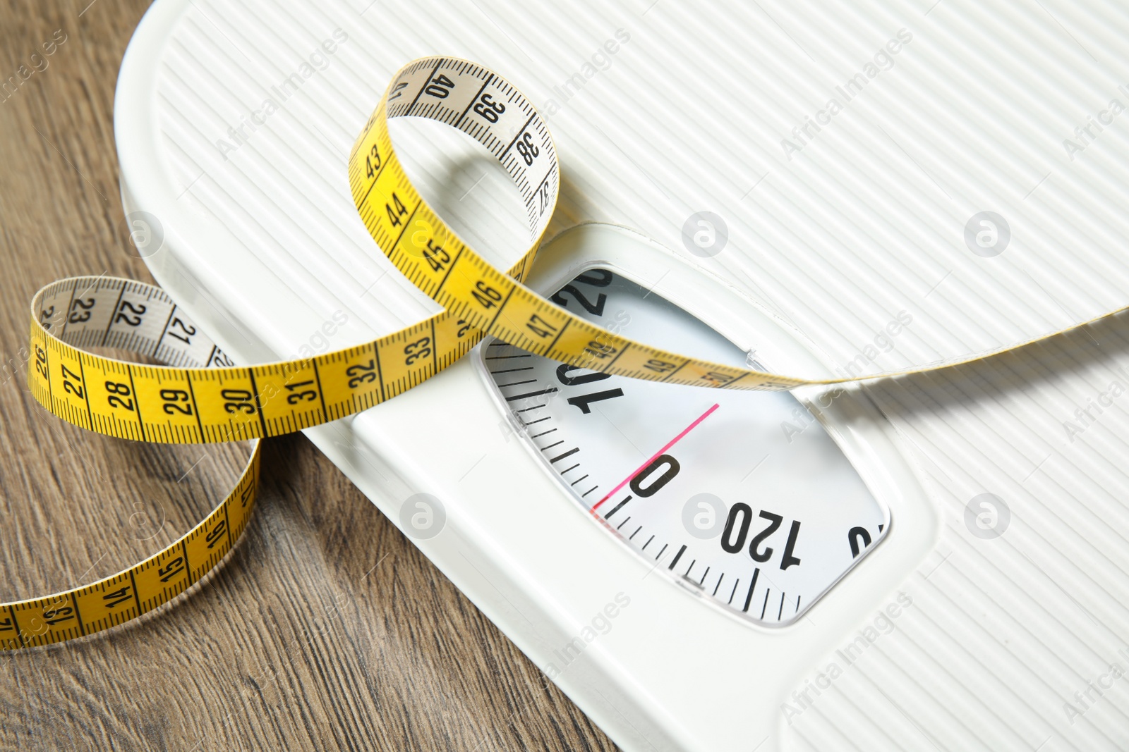 Photo of Scales and measuring tape on wooden background, closeup. Weight loss