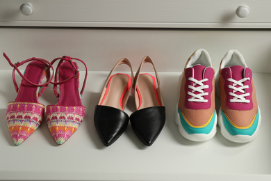 Photo of Different women's shoes in open drawer. Footwear storage