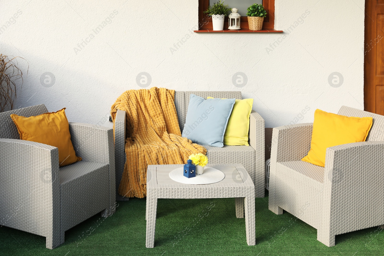 Photo of Beautiful rattan garden furniture, soft pillows, blanket and yellow chrysanthemum flowers outdoors