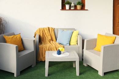 Photo of Beautiful rattan garden furniture, soft pillows, blanket and yellow chrysanthemum flowers outdoors