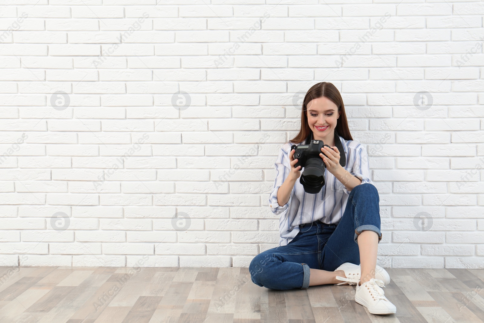 Photo of Professional photographer with modern camera near white brick wall. Space for text