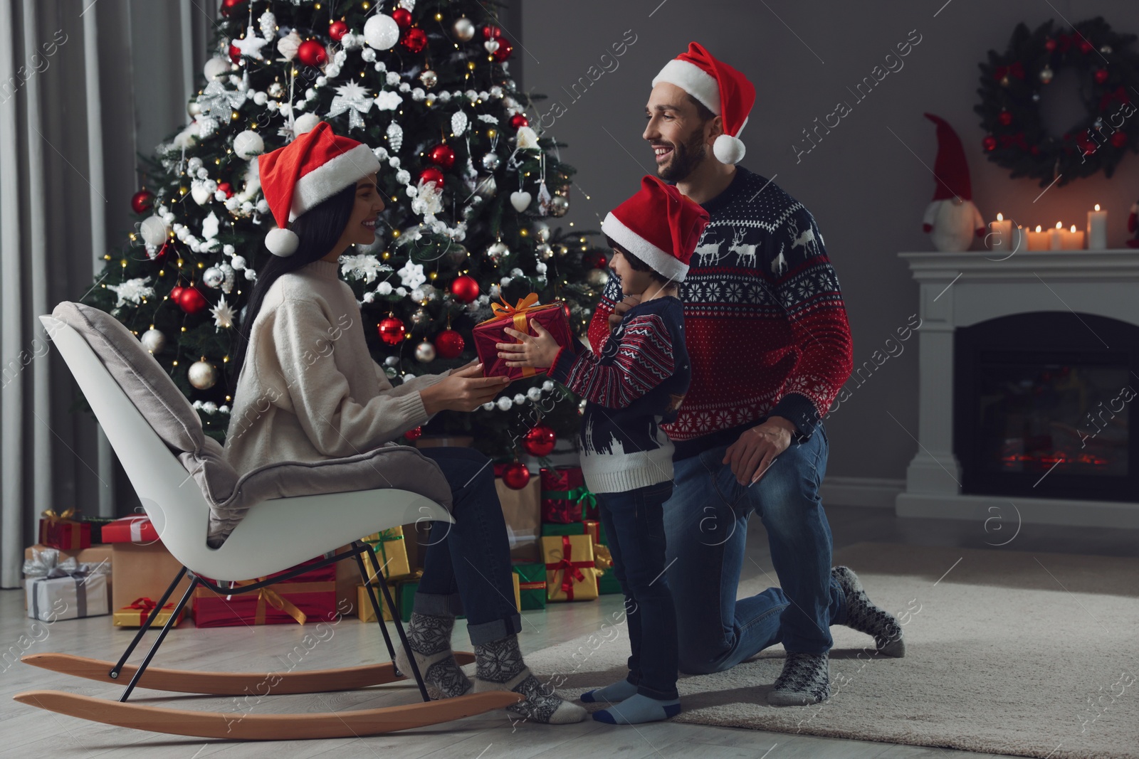 Photo of Father with his cute son presenting gift to mother at home. Christmas celebration