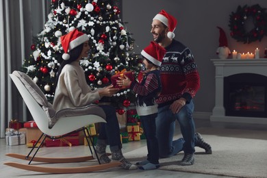 Photo of Father with his cute son presenting gift to mother at home. Christmas celebration