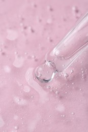 Photo of Pipette with cosmetic serum on pink background, closeup