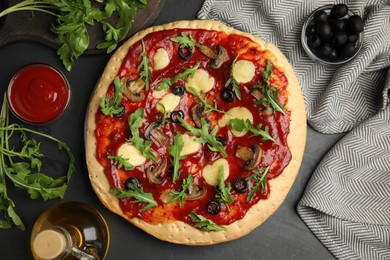 Photo of Pita pizza with cheese, olives, mushrooms and arugula on black table, flat lay