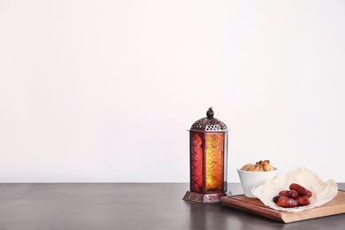 Photo of Muslim lantern Fanous and dried fruits on table against light background. Space for text