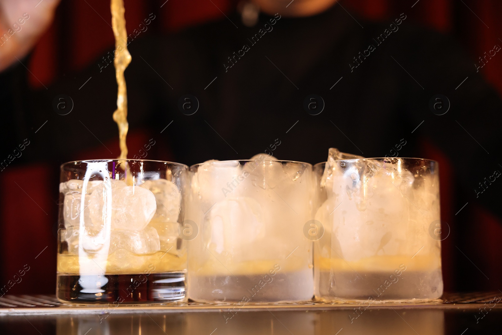 Photo of Bartender pouring energy drink into glass at counter in bar, selective focus