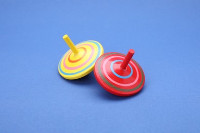 Photo of Two bright spinning tops on blue background. Toy whirligig