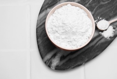 Photo of Bowl and spoon of natural starch on white tiled table, top view. Space for text