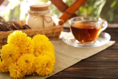 Photo of Beautiful yellow chrysanthemum flowers on wooden table. Space for text