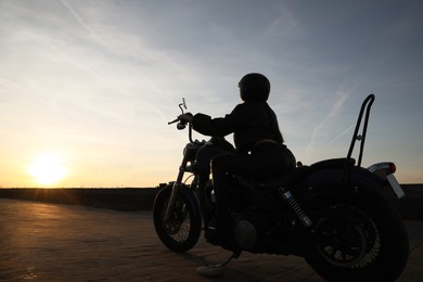Photo of Woman in helmet riding motorcycle at sunset
