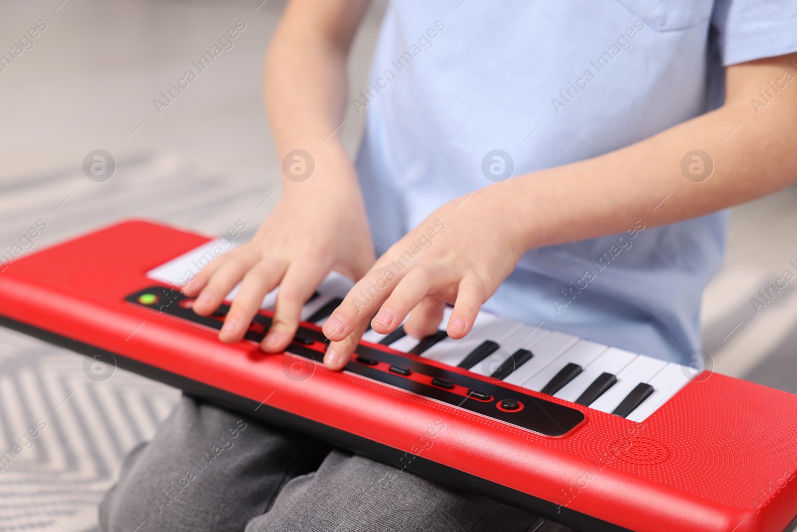 Photo of Little boy playing toy piano at home, closeup