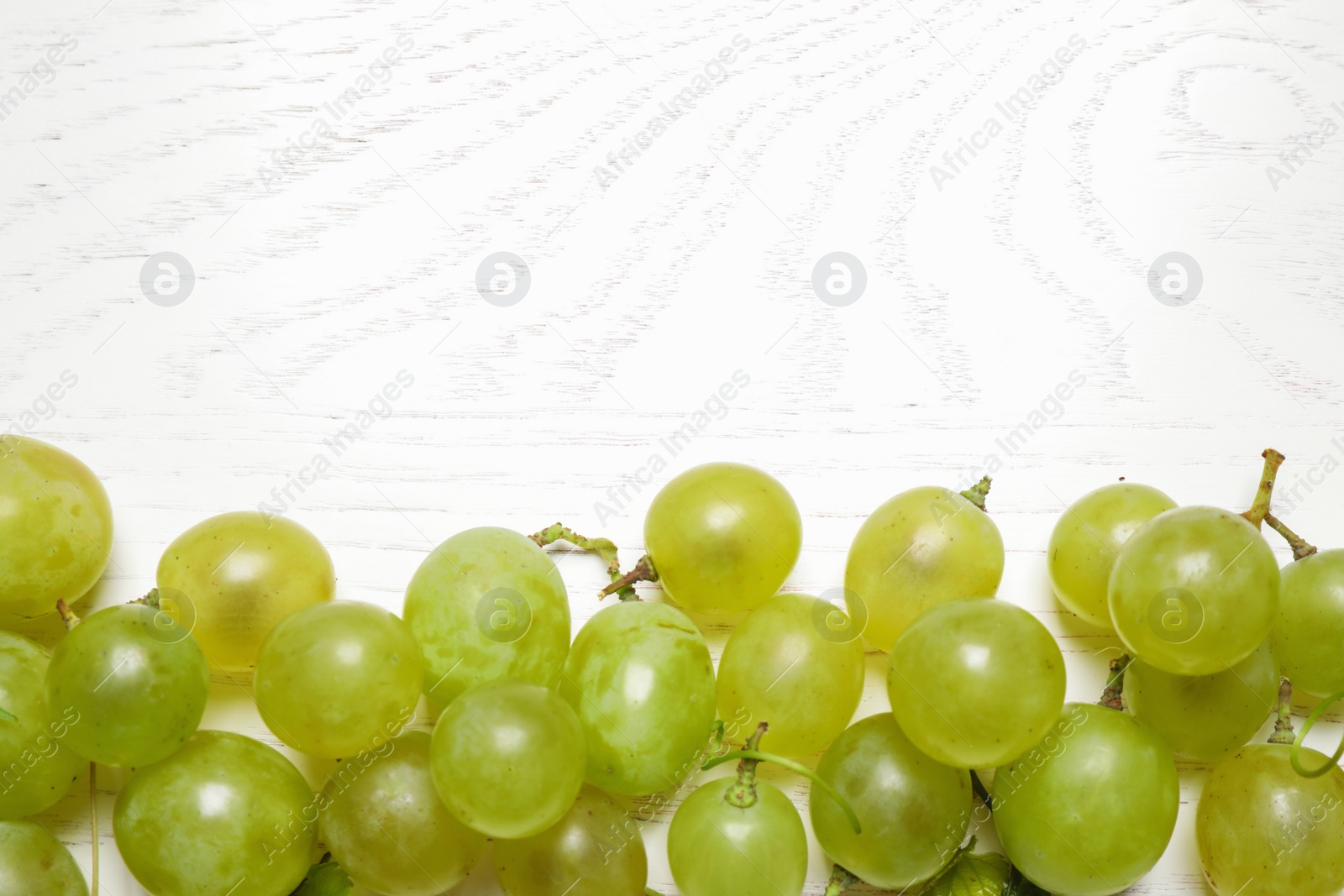 Photo of Flat lay composition with fresh ripe juicy grapes on white wooden table, space for text