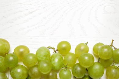 Photo of Flat lay composition with fresh ripe juicy grapes on white wooden table, space for text