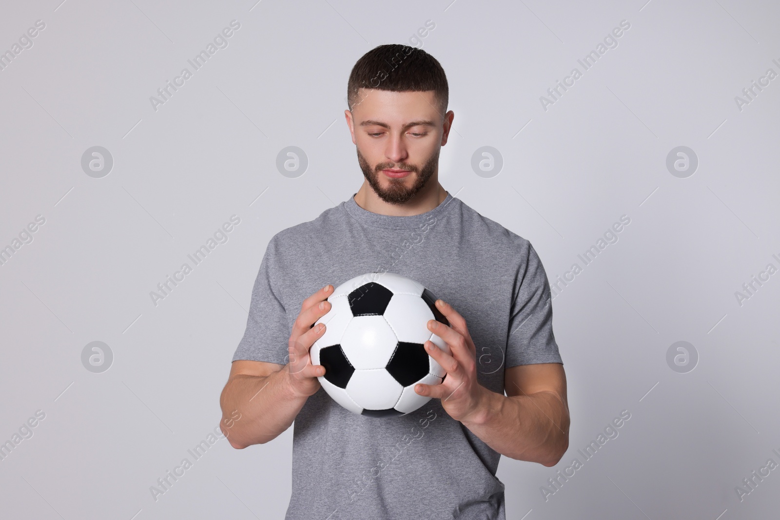 Photo of Athletic young man with soccer ball on light grey background