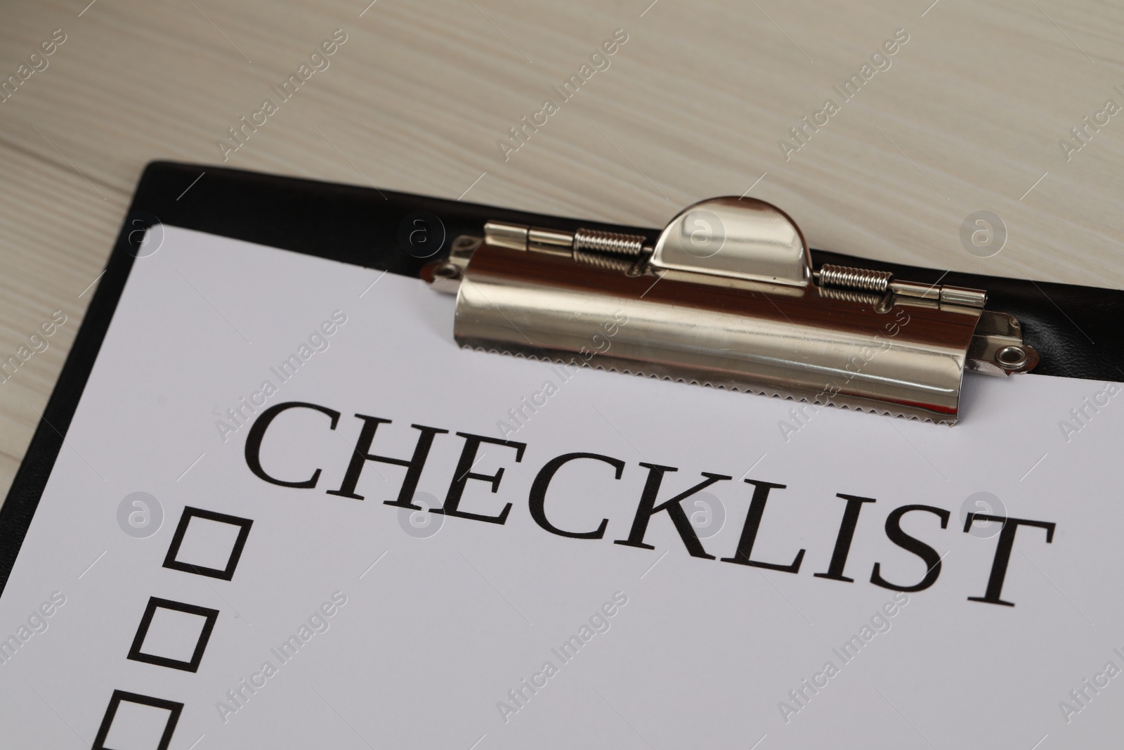 Photo of Clipboard with inscription Checklist on white wooden table, closeup