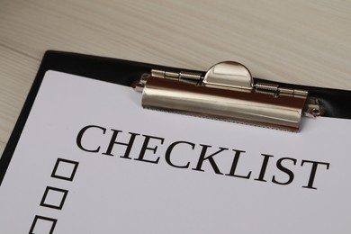 Clipboard with inscription Checklist on white wooden table, closeup