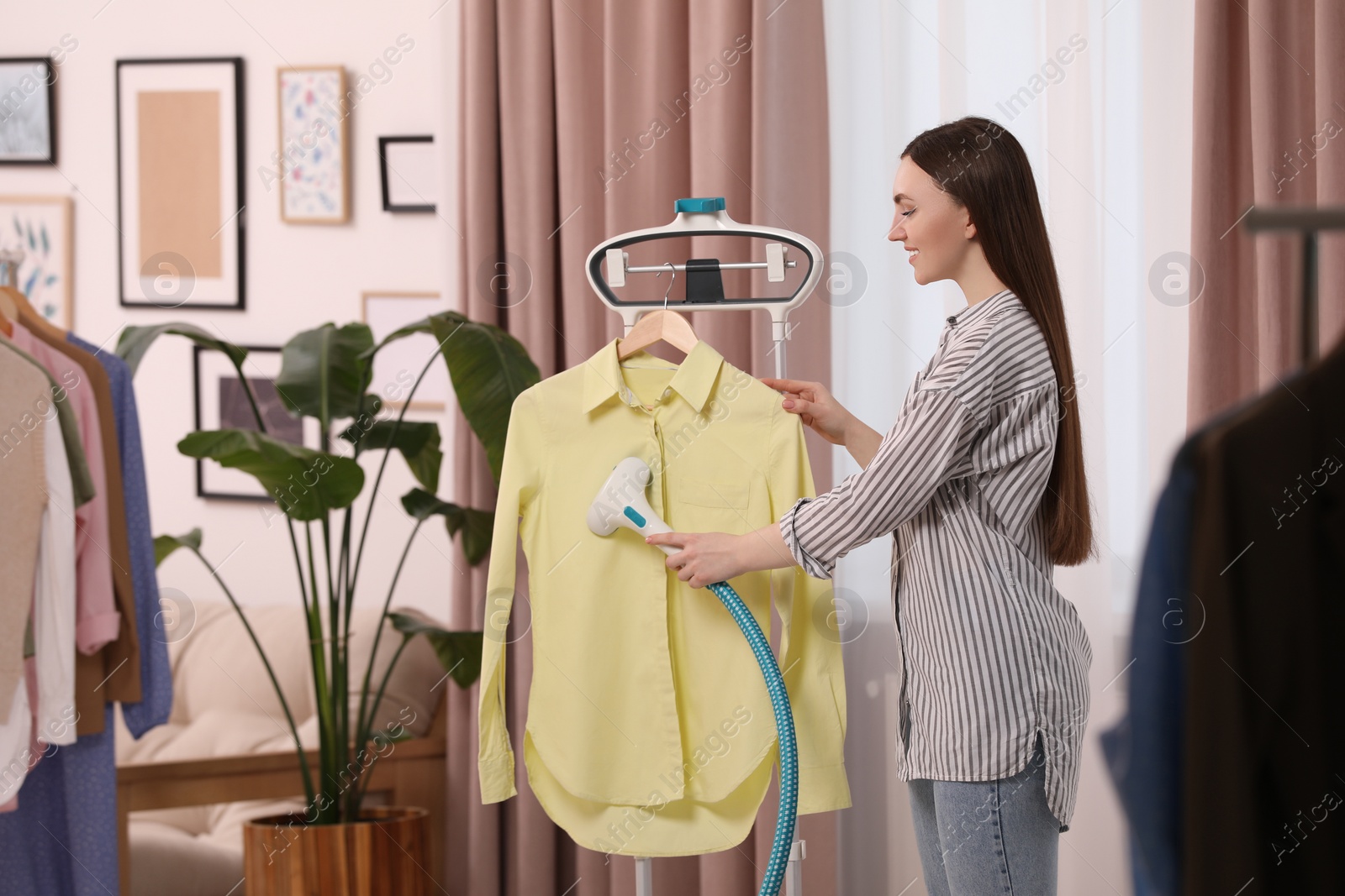 Photo of Woman steaming shirt on hanger at home