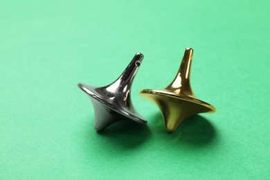 Golden and silver spinning tops on green background, closeup