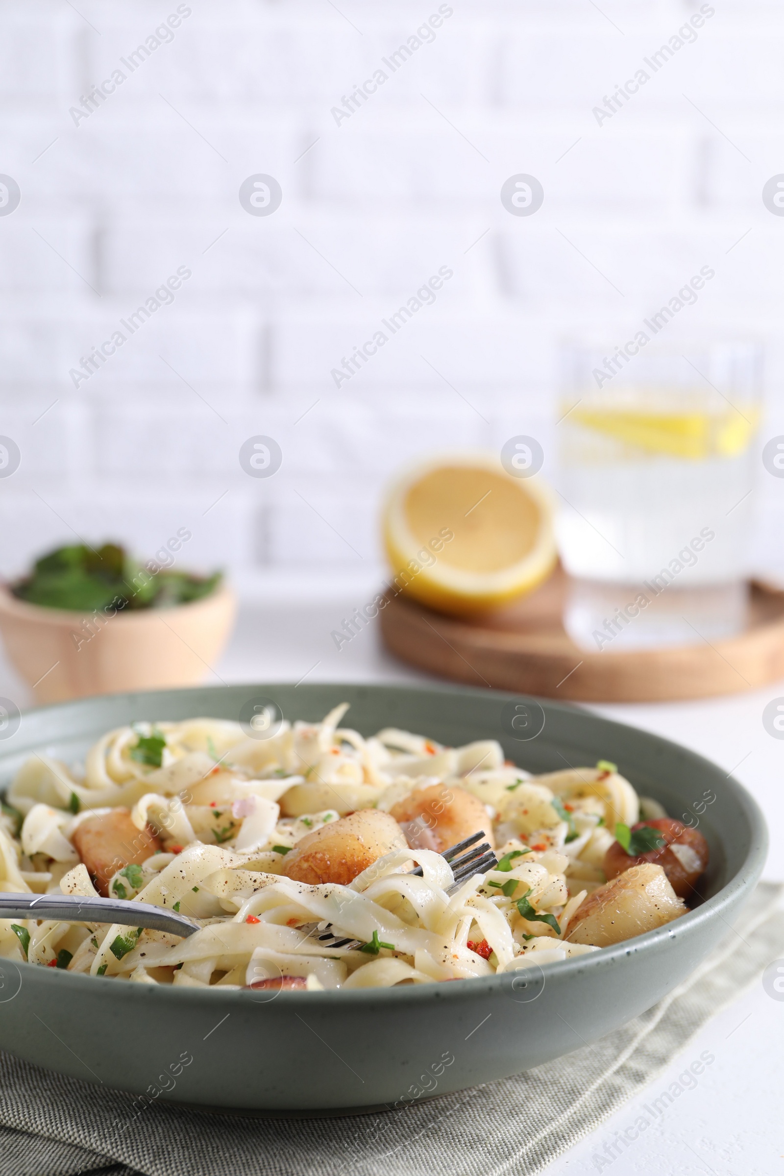 Photo of Delicious scallop pasta with spices in bowl served on white table, closeup