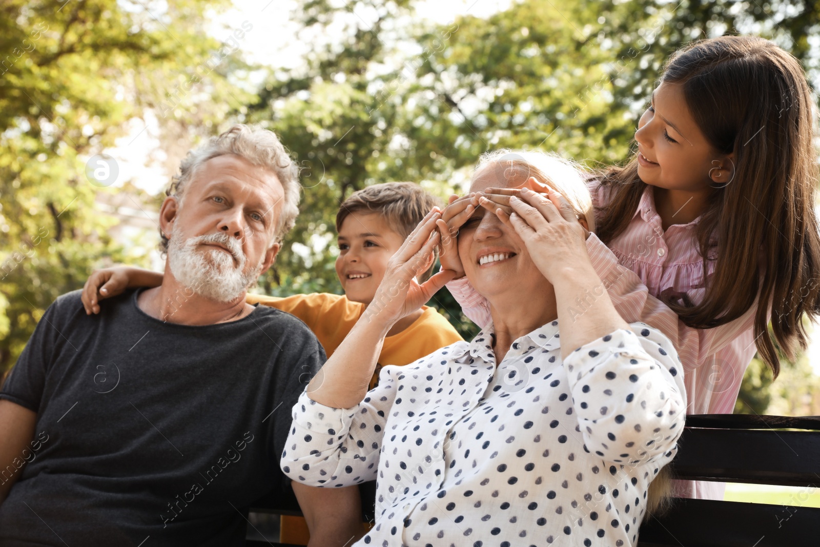 Photo of Happy grandparents with little children having fun together in park