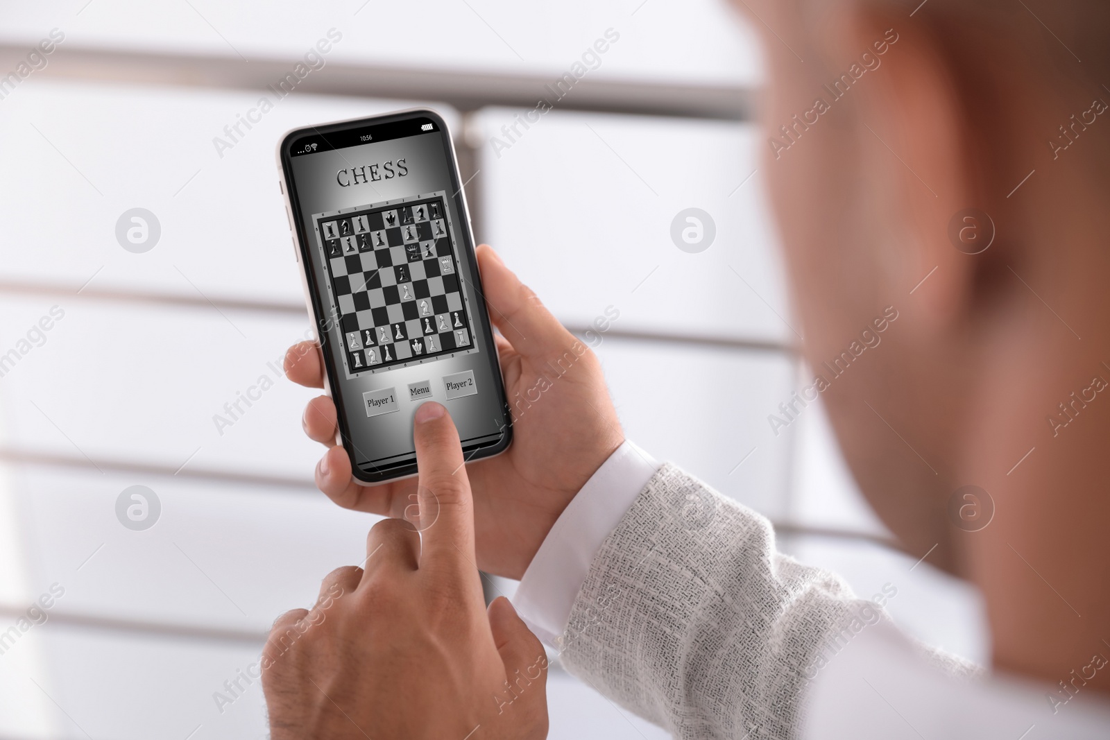 Image of Man playing online chess on smartphone indoors, closeup