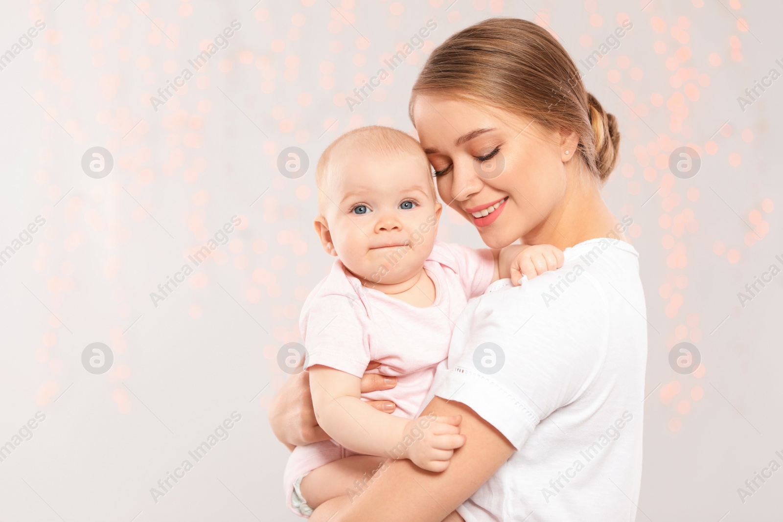 Photo of Portrait of happy mother with her baby against blurred lights. Space for text