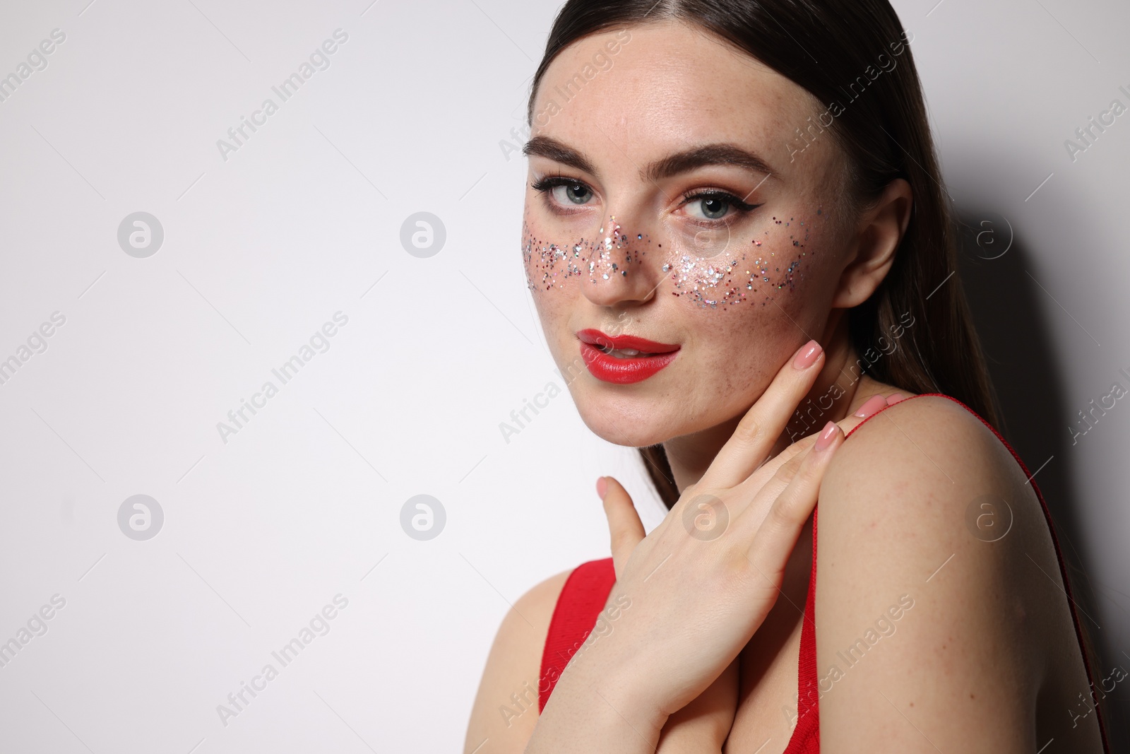 Photo of Beautiful woman with glitter freckles on light background. Space for text