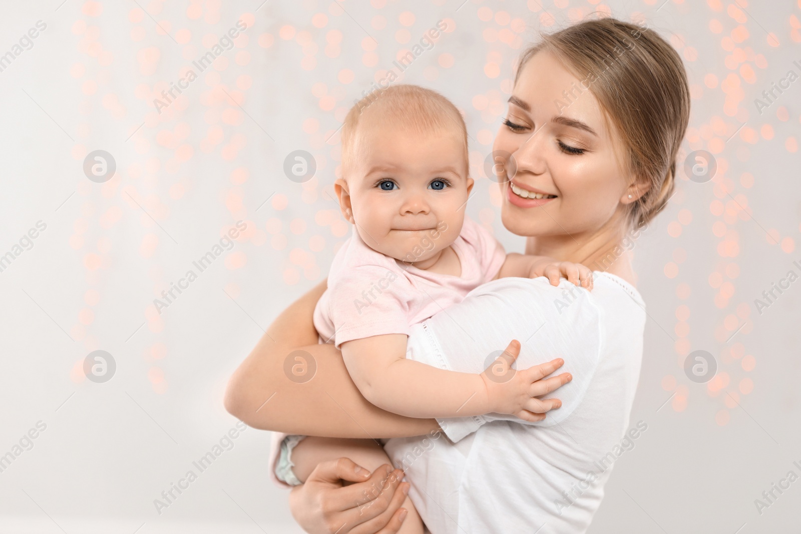 Photo of Portrait of happy mother with her baby against blurred lights