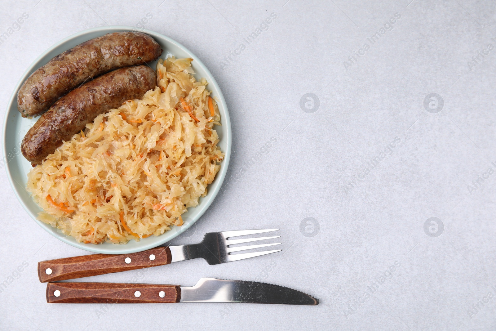 Photo of Plate with sauerkraut and sausages on light table, flat lay. Space for text