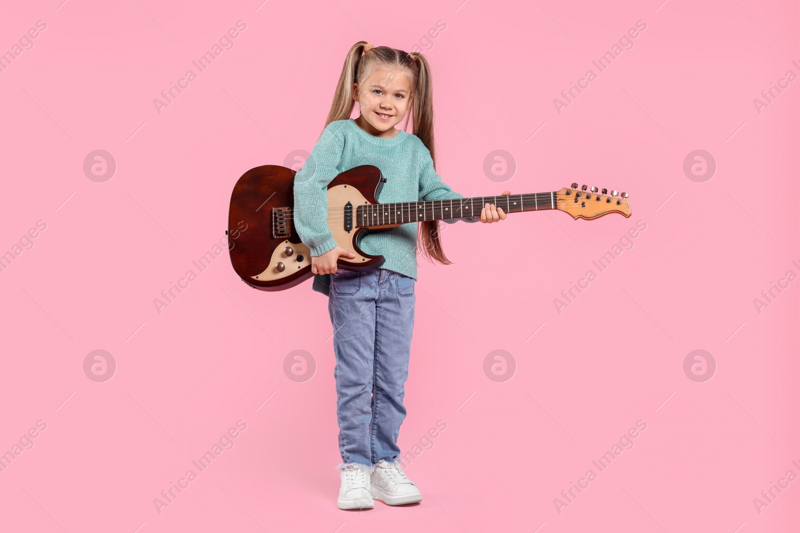 Photo of Happy girl with electric guitar on pink background. Space for text