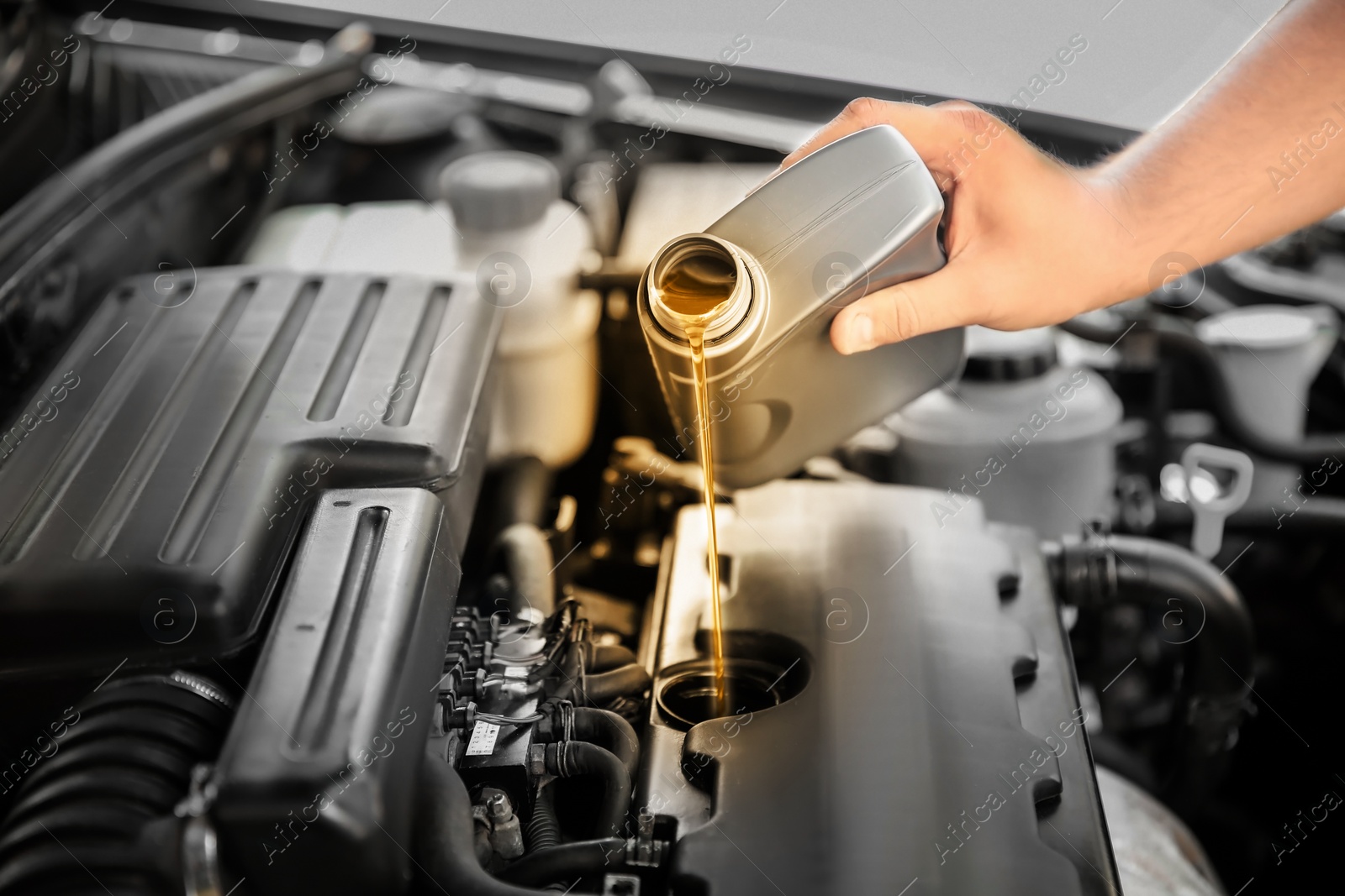 Image of Man pouring motor oil into car engine, closeup. Color accent effect