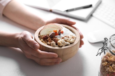 Woman with tasty granola at workplace, closeup