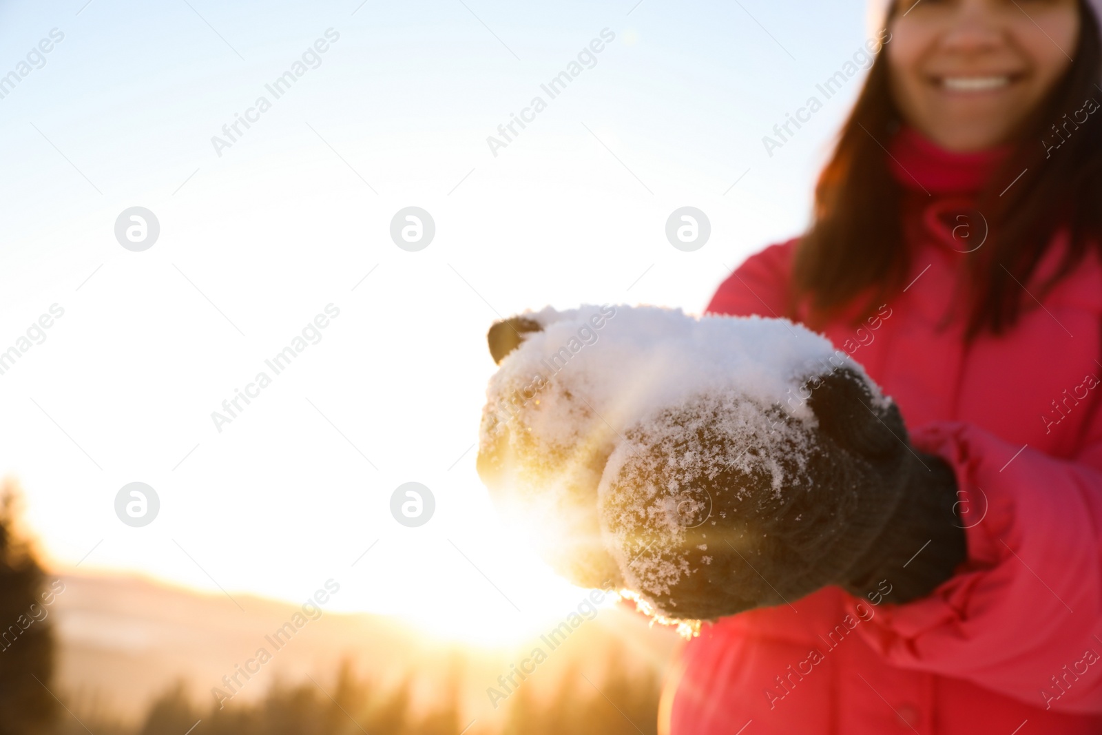 Photo of Woman holding pile of snow outdoors, closeup view with space for text. Winter vacation