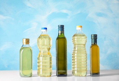 Photo of Bottles of oils on table against color background