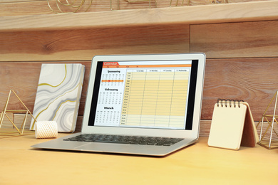 Modern laptop with calendar on screen in office