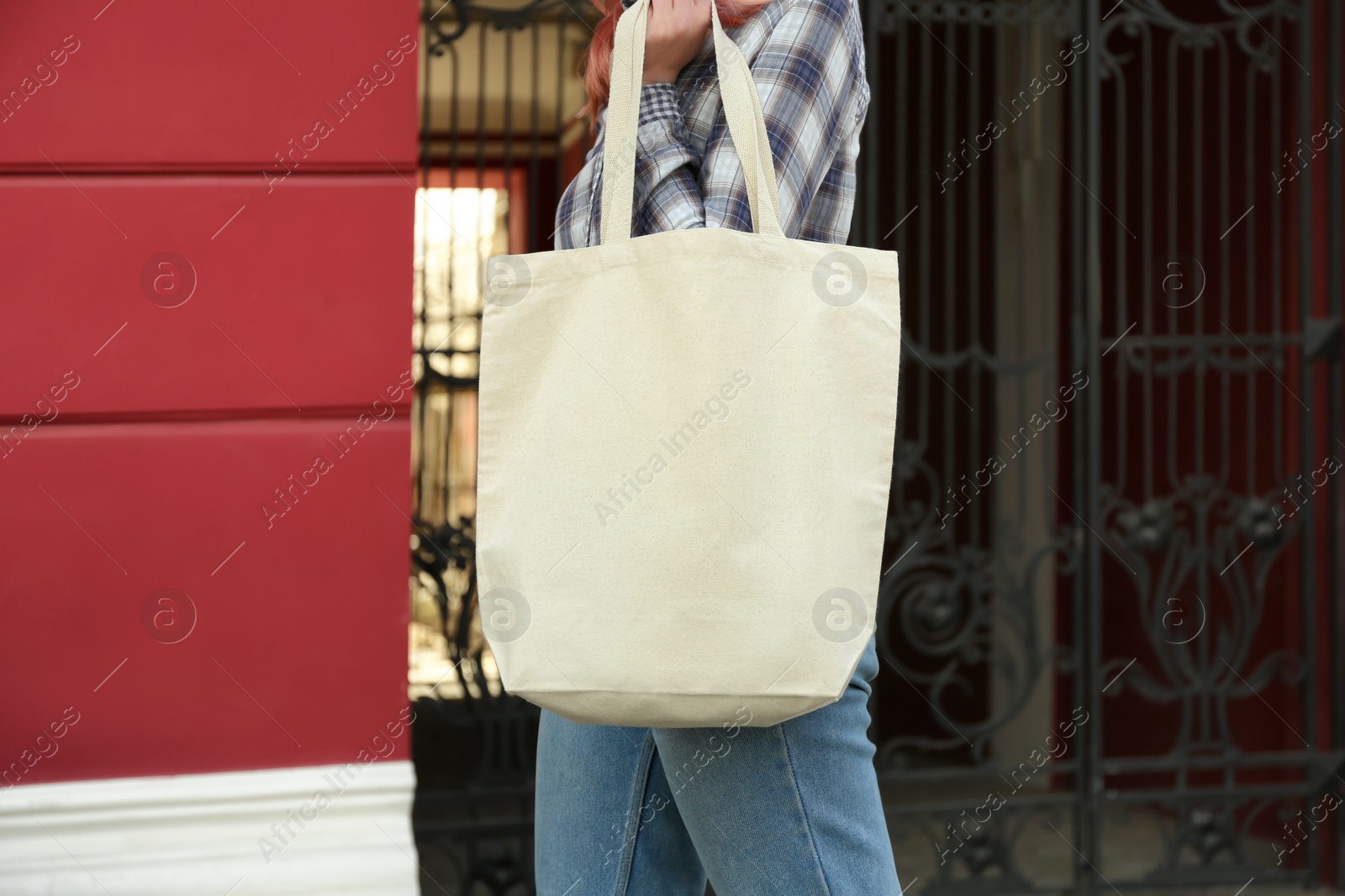 Photo of Young woman with cotton bag on city street, closeup. Mockup for design