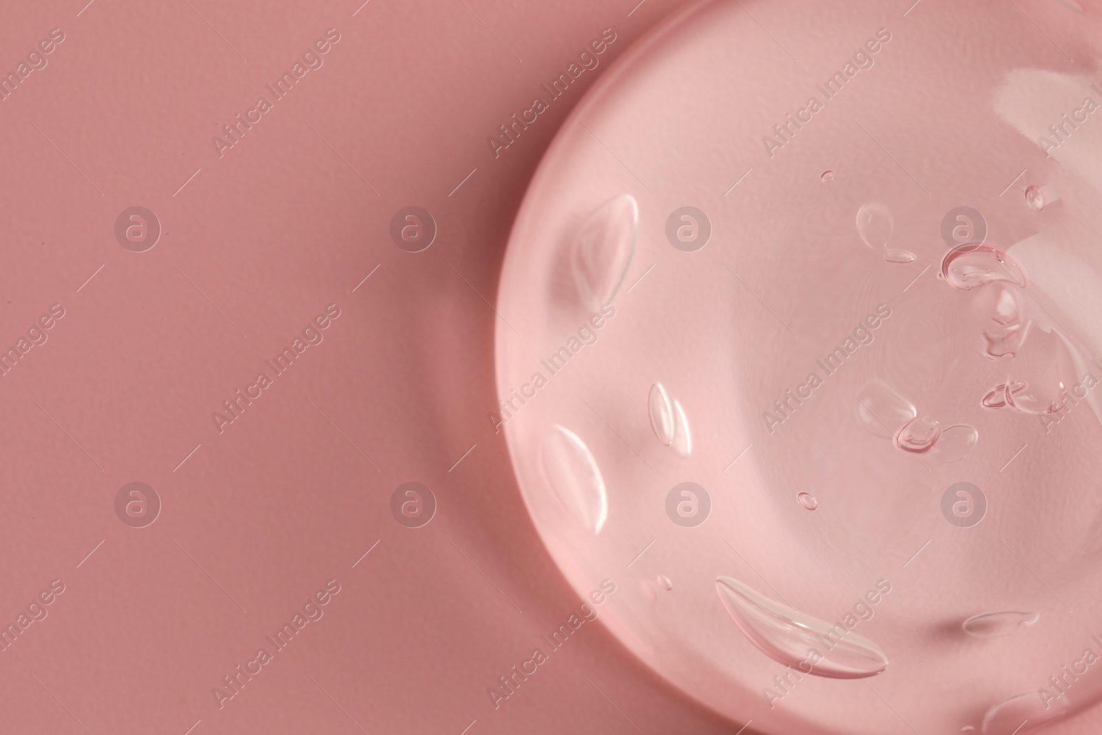 Photo of Sample of clear cosmetic gel on pink background, top view. Space for text