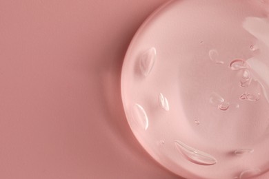 Sample of clear cosmetic gel on pink background, top view. Space for text