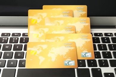 Photo of Many golden credit cards on laptop, closeup
