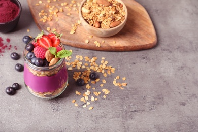 Photo of Delicious acai dessert with granola and berries served on grey table. Space for text