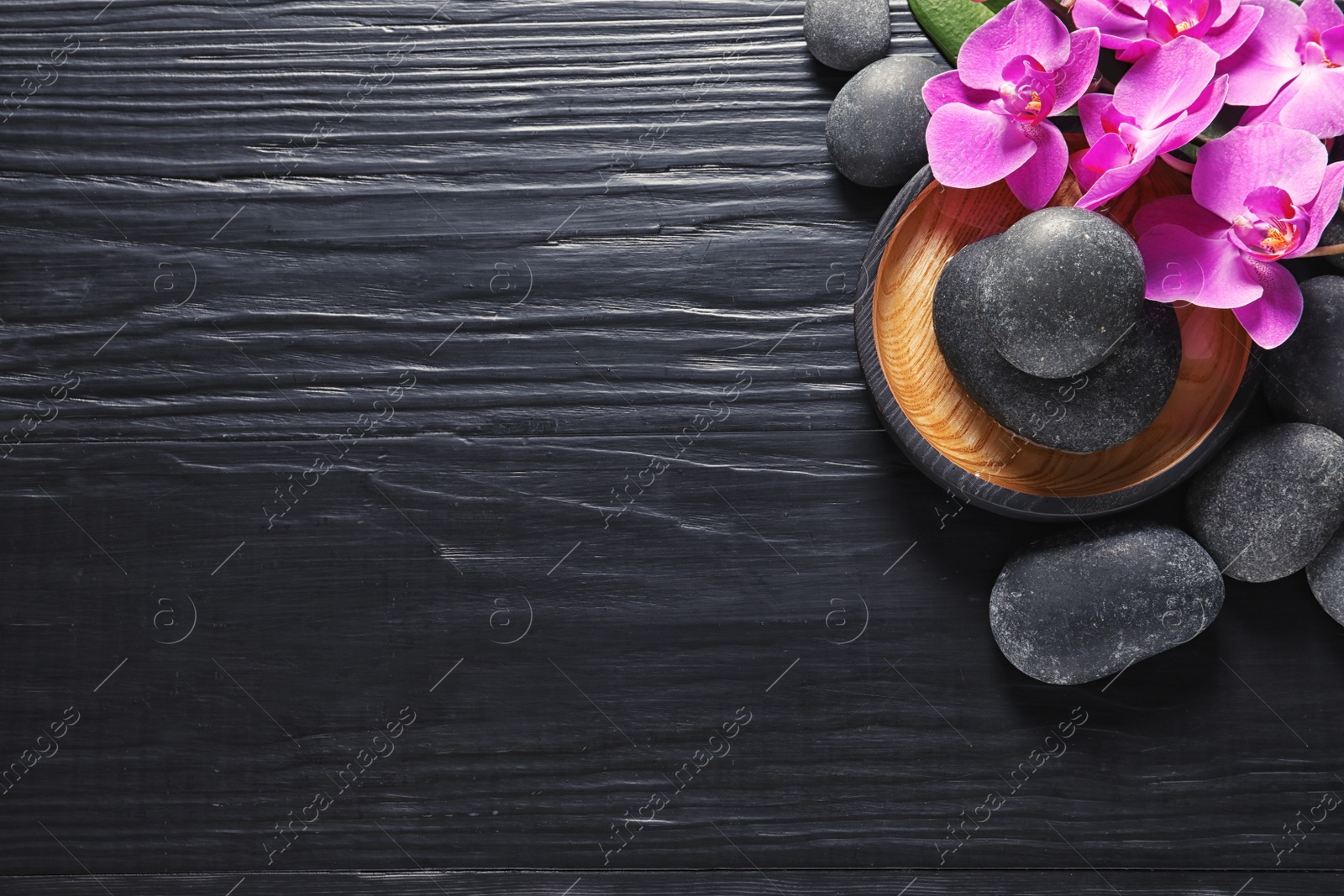 Photo of Composition with orchid flowers and spa stones on dark wooden background, top view. Space for text